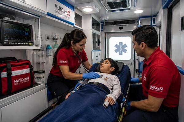 Paramédicos de MultiCare A+1 valorando a un paciente pediátrico en la camilla dentro de la ambulancia
